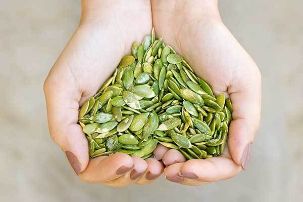 raw pumpkin seeds in woman hands